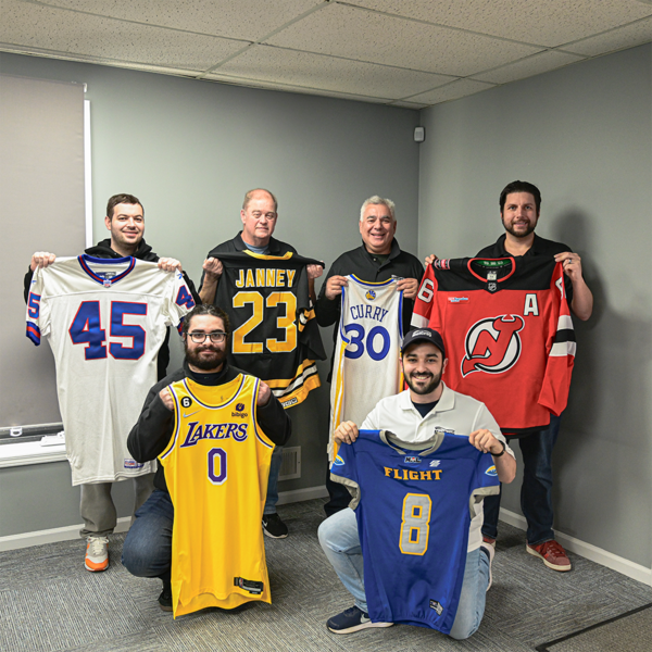 Members of MeiGray staff showing off various Game-Worn Jerseys.